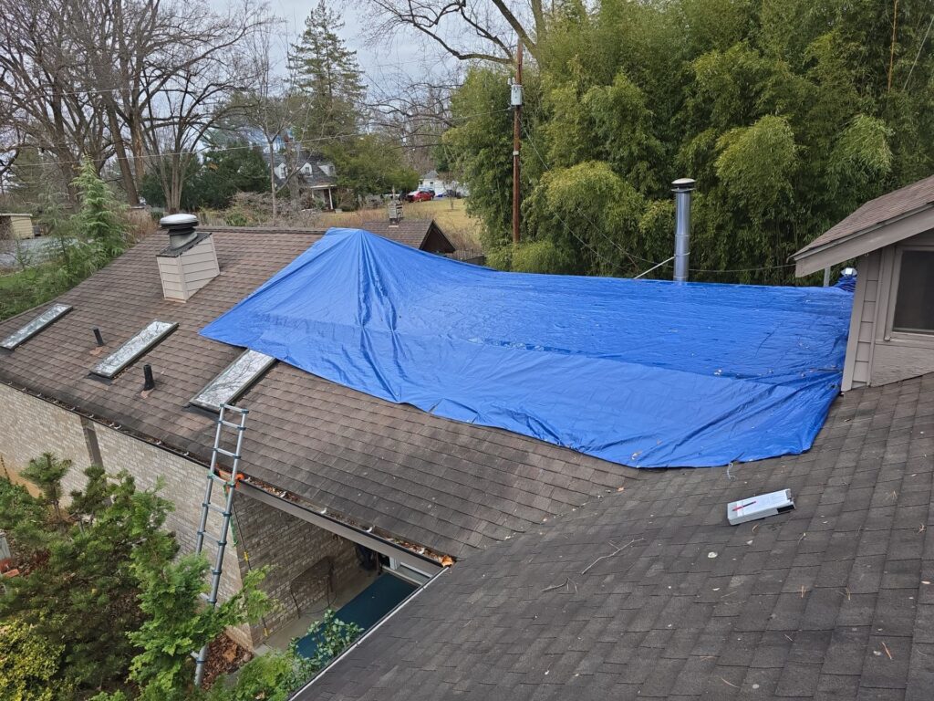 Emergency roofer installing tarp on storm-damaged roof in Georgia